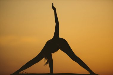 Genç kadın batımında yoga dağda pratiği yapıyor. Pratik yoga açık genç kadın silüeti.