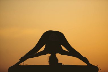 Genç kadın batımında yoga dağda pratiği yapıyor. Pratik yoga açık genç kadın silüeti.