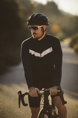 Profesyonel yol bisiklet yarışçısı poz. Erkek dağ yol bisikleti günbatımında Bisiklete binme.