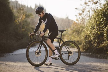 Profesyonel yol bisiklet yarışçısı poz. Erkek dağ yol bisikleti günbatımında Bisiklete binme.