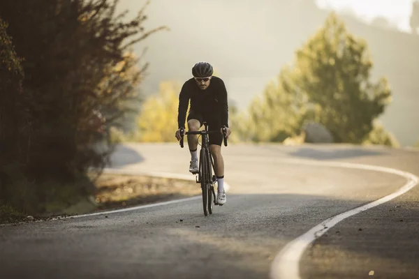 アクションのプロ ロード自転車レーサー 男性夕暮れ山自転車道をサイクリング — ストック写真