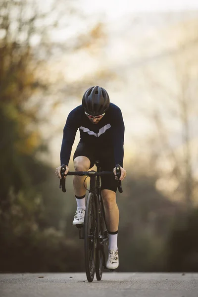 アクションのプロ ロード自転車レーサー 男性夕暮れ山自転車道をサイクリング — ストック写真