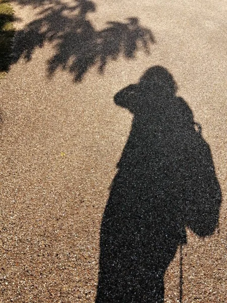 A woman\'s shadow on a brown earth floor.