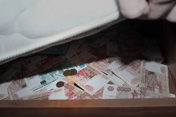 Storing money under the bed. Russian rubles are hidden in banknotes and coins.