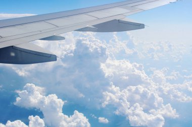 Bir uçağın kanatları altında beyaz bulutlardan oluşan gökyüzü manzarası
