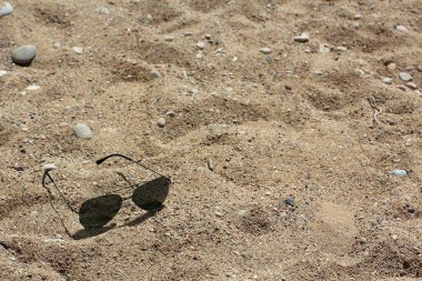 Güneş gözlükleri kumda yatıyor.