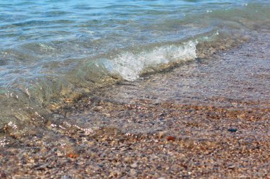 Beyaz tepeli bir deniz dalgası yükselir ve kumlu plaja çarpar. Dalga arkaplan fotoğrafı.