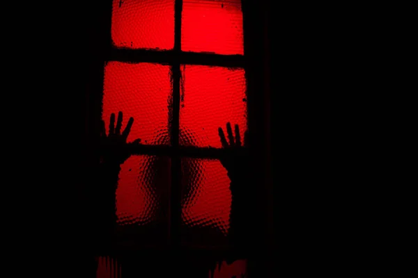 Silhouette einer Person, die Fenster im Dunkeln berührt — Stockfoto
