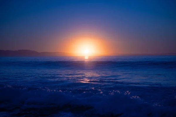 Coucher de soleil sur l'océan avec des vagues s'écrasant sur le rivage — Photo