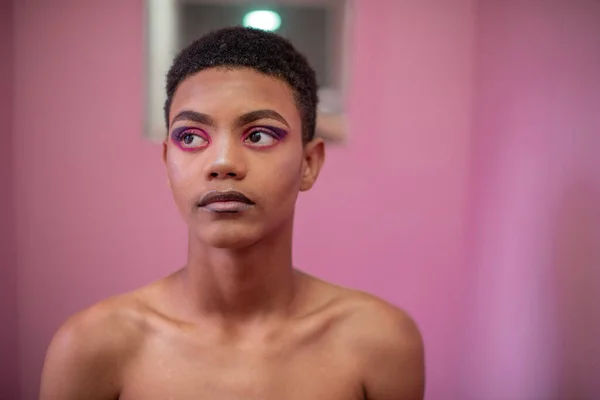Porträt eines jungen queeren Mannes im Zimmer mit rosa Wand — Stockfoto