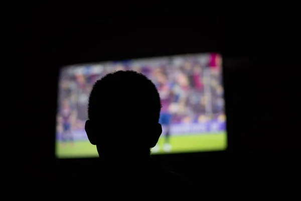 Силуэт человека, смотрящего телевизор в темноте — стоковое фото