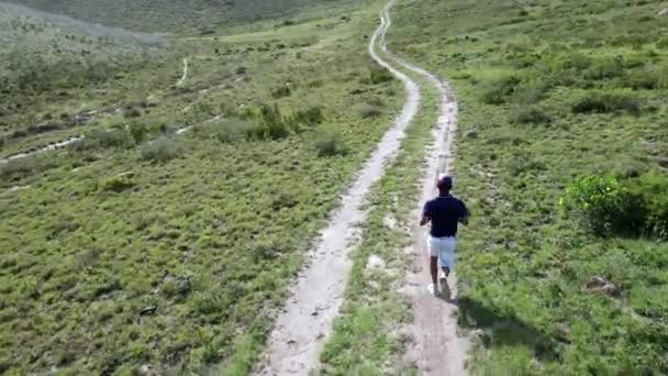 Veduta aerea del giovane ragazzo che corre attraverso il sentiero in natura — Video Stock