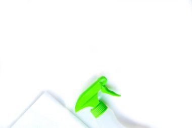 Beyaz arka planda evi yıkamak için kimyasallarla dolu çeşitli plastik şişeler. Mesaj için yer var. Yeşil bir sprey tabancası ve bez parçasıyla.