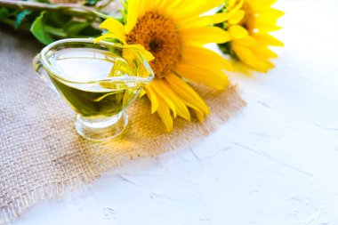 Ayçiçeği yağı cam tencereye döküldü. Çiçeklerin yanında. beyaz arkaplan