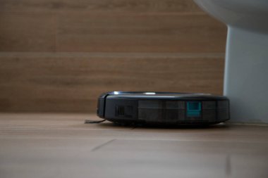 Siyah robot ahşap zemini olan bir banyoyu süpürüyor. Teknoloji konsepti.