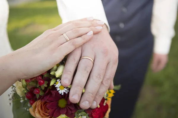 Hands of bride and groom with flower bouquet — Stock Photo, Image