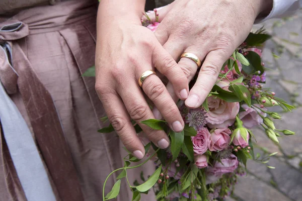 Hands of bride and groom with flower bouquet — Stock Photo, Image