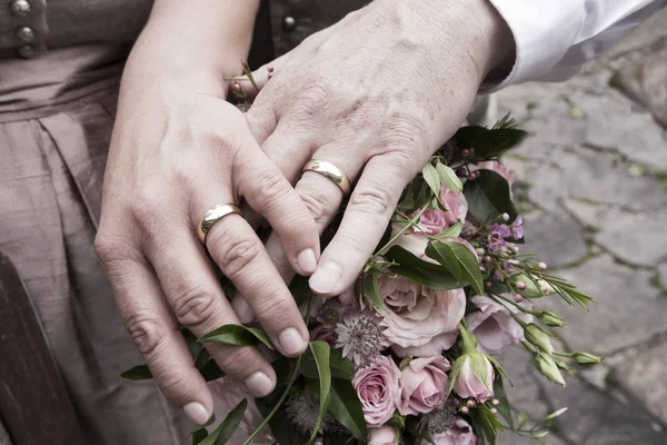 Mains de mariée et marié avec bouquet de fleurs — Photo