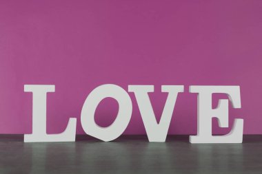 Kelime aşk pembe backgrou önünde beyaz harflerle yazılmış