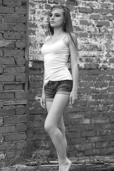 T恤和短裤的年轻女孩站在砖墙上 — 图库照片