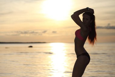 Bikini deniz günbatımı arka plan üzerinde genç kız