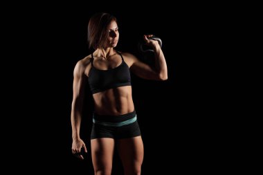 siyah bir arka plan üzerinde ağırlığı ile nişanlı Genç Kas spor kız