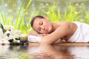 Bir kadın masaj yatağında uzanıp dinleniyor.