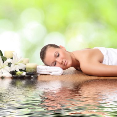 Bir kadın masaj yatağında uzanıp dinleniyor.