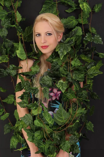 一个年轻的金发女郎在树叶的肖像 — 图库照片