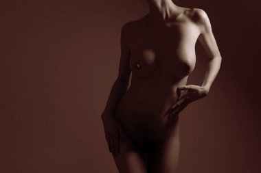 Güzel kızın çıplak bedeni karanlık arka planda.