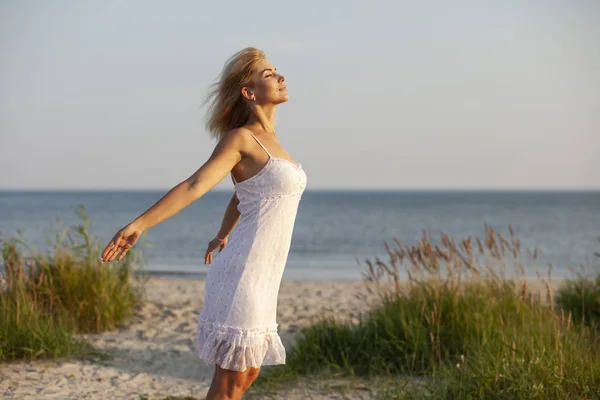 Glückliche Frau am Strand bei Sonnenuntergang — Stockfoto