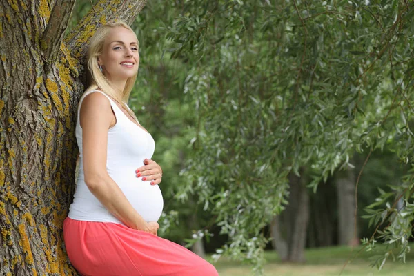 Mladá šťastná těhotná dívka v parku — Stock fotografie