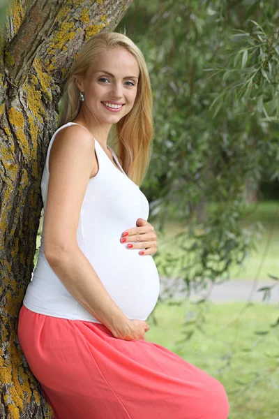 Ung glad gravid flicka i parken — Stockfoto