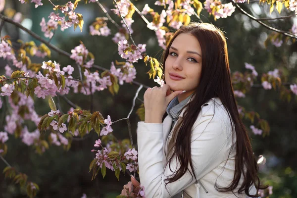 Ung flicka poserar vid busken med vårblommor — Stockfoto