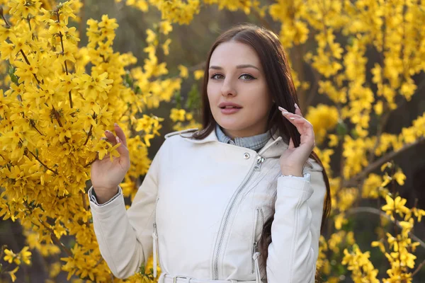 Junges Mädchen posiert am Strauch mit Frühlingsblumen — Stockfoto