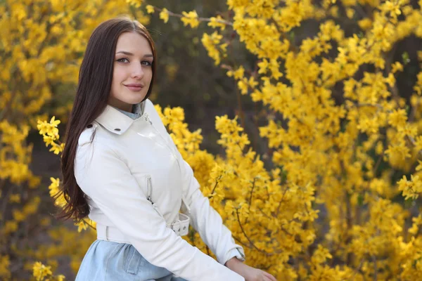 Молодая девушка позирует у куста с весенними цветами — стоковое фото