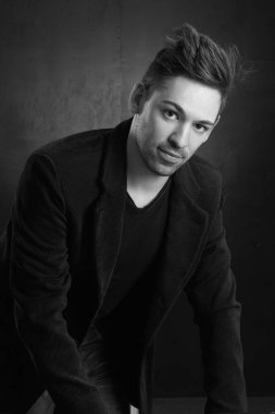 Siyah bir arka planda ceketli genç şık bir adam.