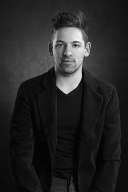 Siyah bir arka planda ceketli genç şık bir adam.