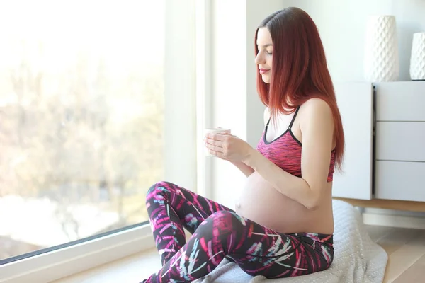 Mulher grávida com xícara de chá na janela — Fotografia de Stock