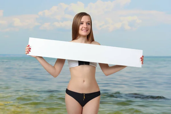 Sexy young woman posing in bikini showing blank placard board