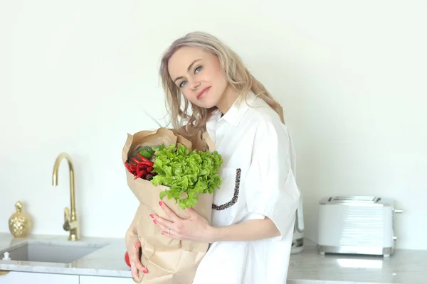 Молодая позитивная улыбающаяся женщина с овощами на кухне — стоковое фото