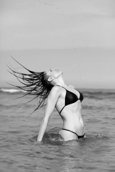 穿着黑色比基尼的年轻女孩在海滩上 — 图库照片