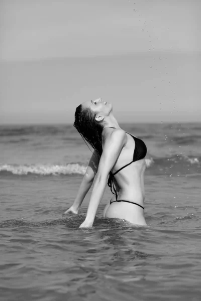 Junges Mädchen im schwarzen Bikini am Strand — Stockfoto