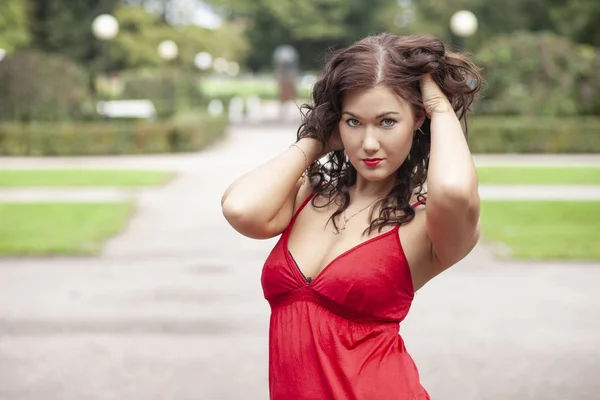 Young sexy girl in red dress in the park — Stock Photo, Image