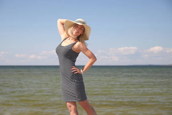 Gelukkige vrouw op het strand op zee bij zonsondergang. — Stockfoto