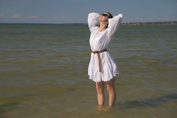 Jovem menina feliz em um vestido branco junto ao mar — Fotografia de Stock