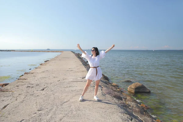 Giovane ragazza felice in un abito bianco in riva al mare — Foto Stock