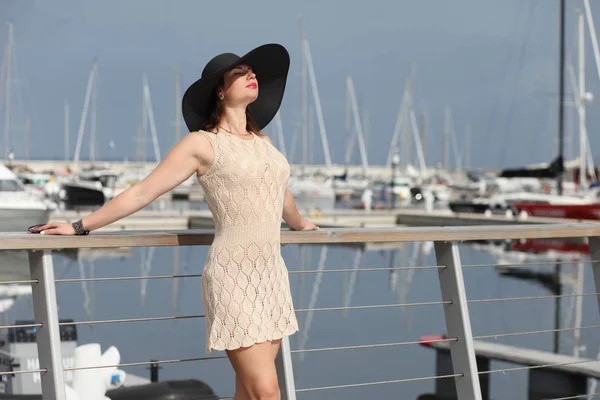Young woman with hat standing near boats in marina — Stock Photo, Image