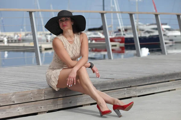 Ung kvinna med hatt nära båtar i småbåtshamnen — Stockfoto