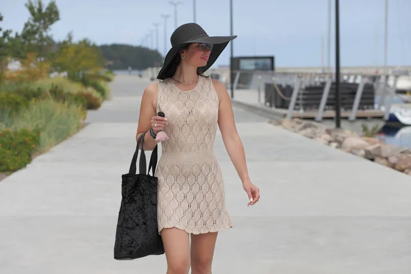 woman with bag and head walks down the street